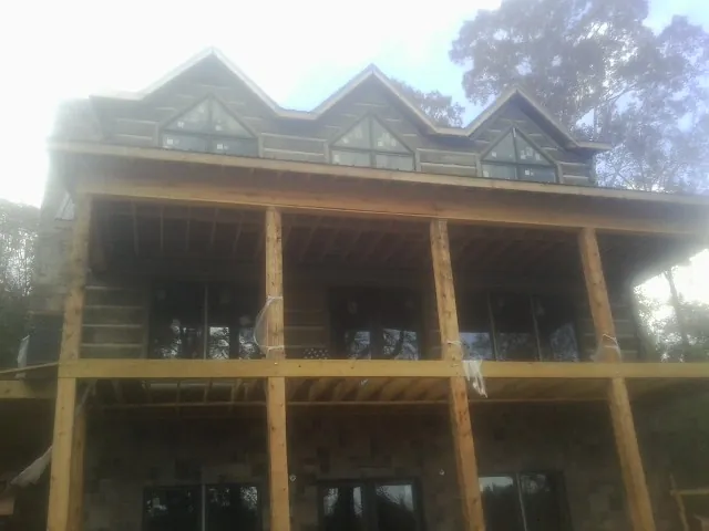 Dormers and porch framing on a large log home under construction — Roof Coating work by our crew in Lakeview