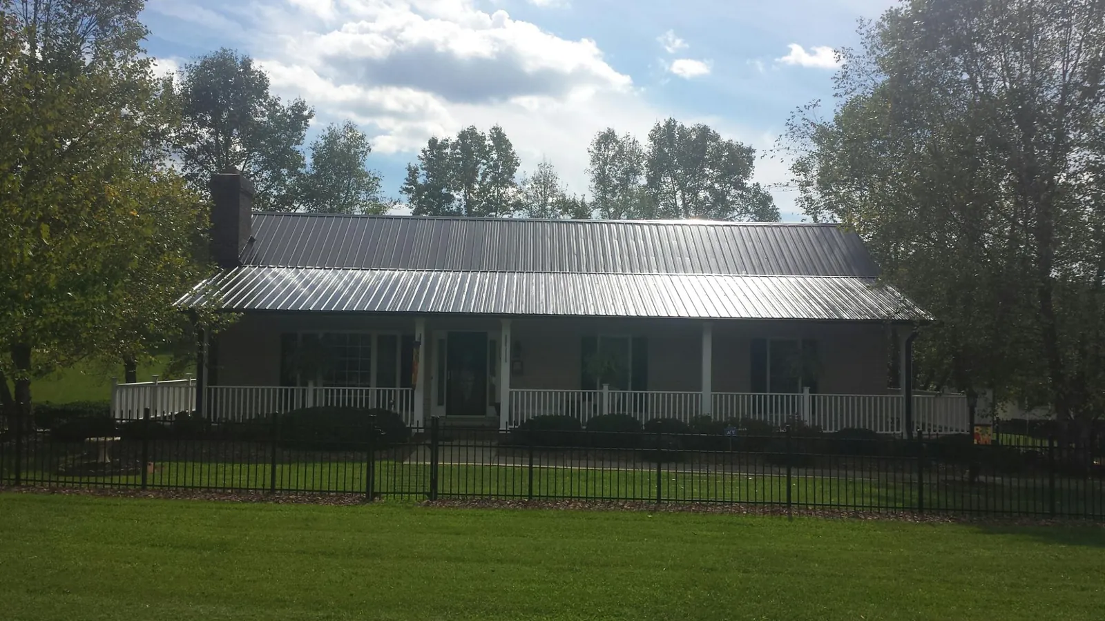 Gray metal roof on a brick ranch with a full width front porch — Gutter Guard Installation work by our crew in Lakeview
